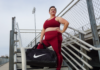 brianne wearing a matching maroon workout set from torrid with a nike bag on a bleacher