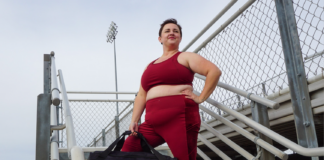 brianne wearing a matching maroon workout set from torrid with a nike bag on a bleacher