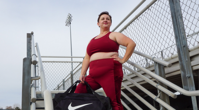 brianne wearing a matching maroon workout set from torrid with a nike bag on a bleacher