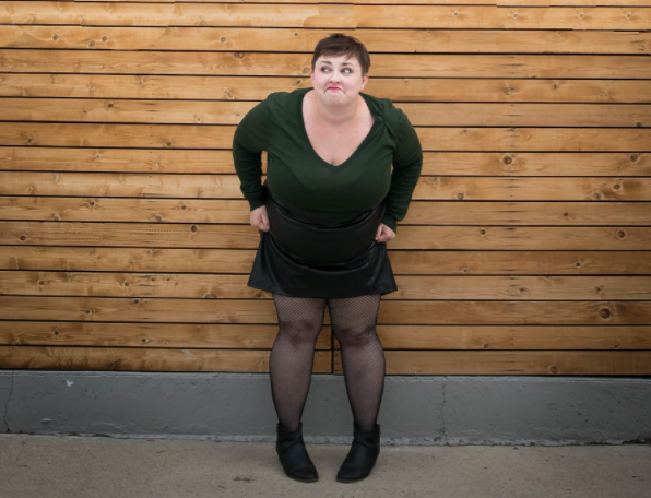 Plus size blogger styling a plus size leather skirt with a sweater and fishnets
