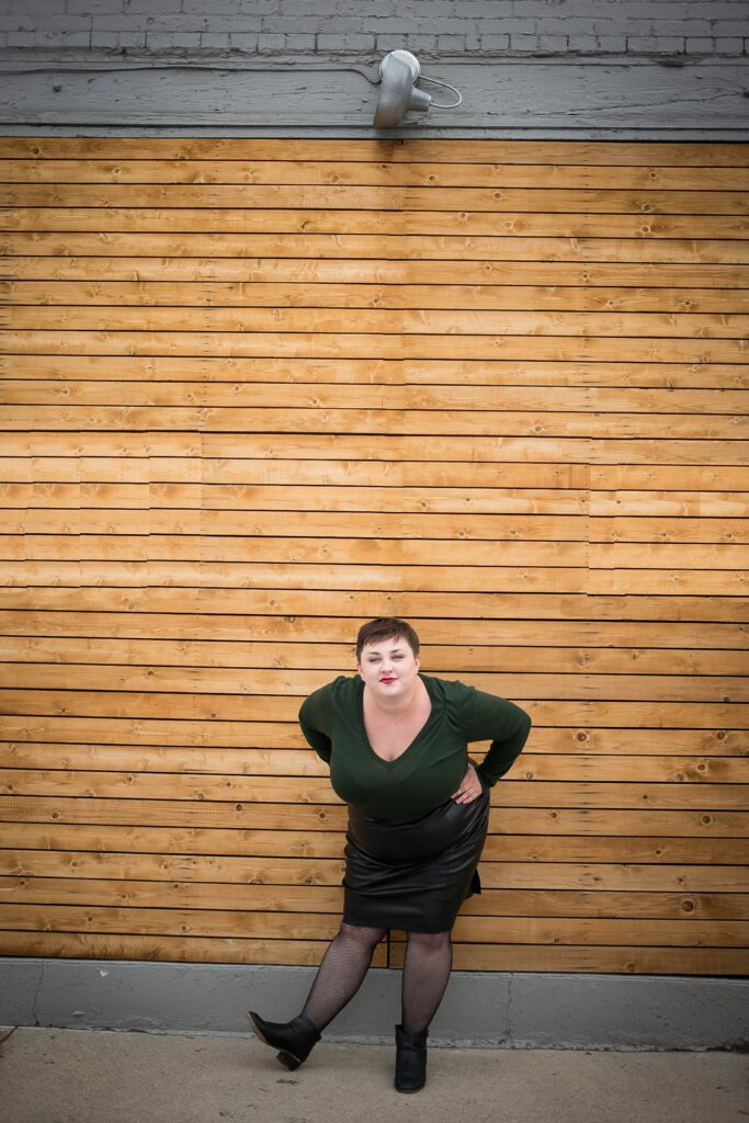 Sassy and fun plus size blogger styling a plus size leather skirt with a sweater and fishnets