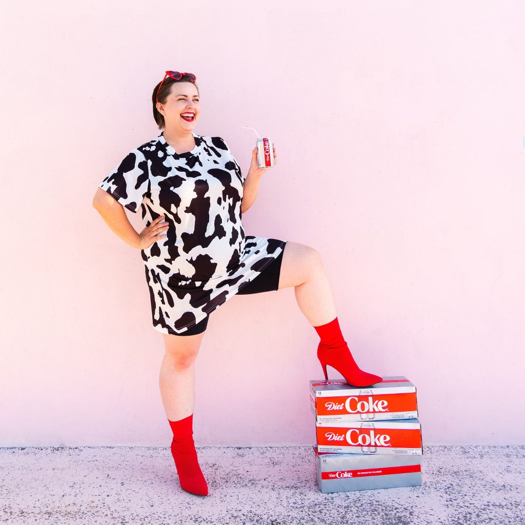 Blogger holding diet coke in cowprint dress laughing in utah