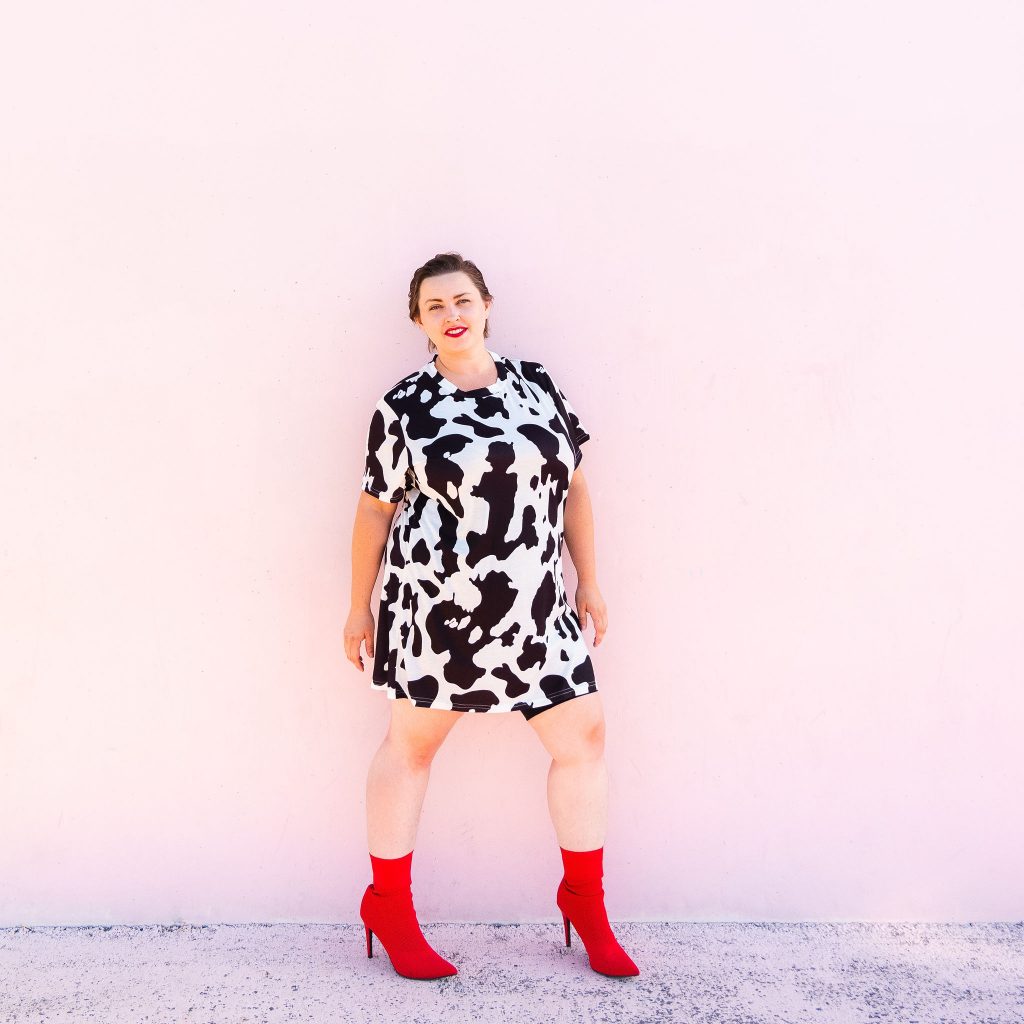 Fashion blogger and model in cowprint dress with red boots