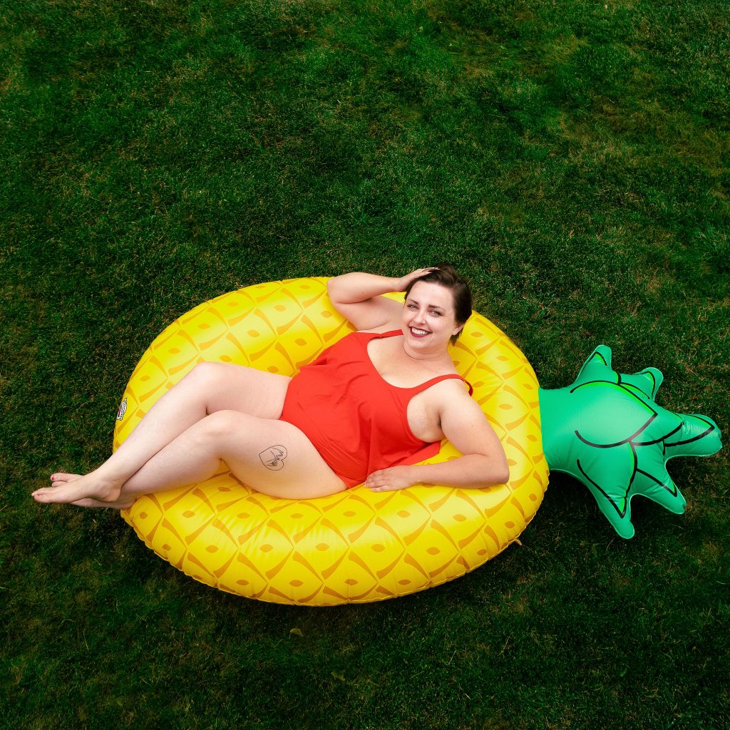 Plus size blogger in backyard with pool floatie pineapple.jpg