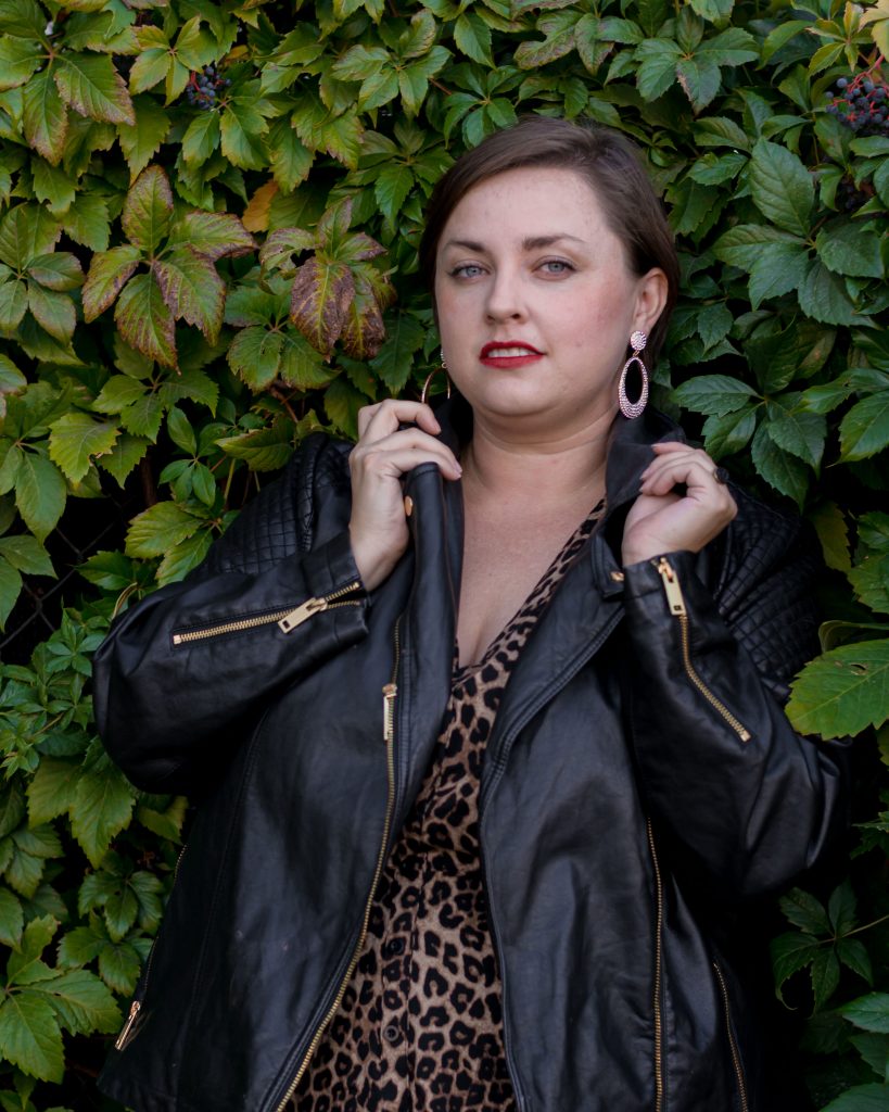 image of The Huntswoman in a leather jacket against a green leafy backdrop
