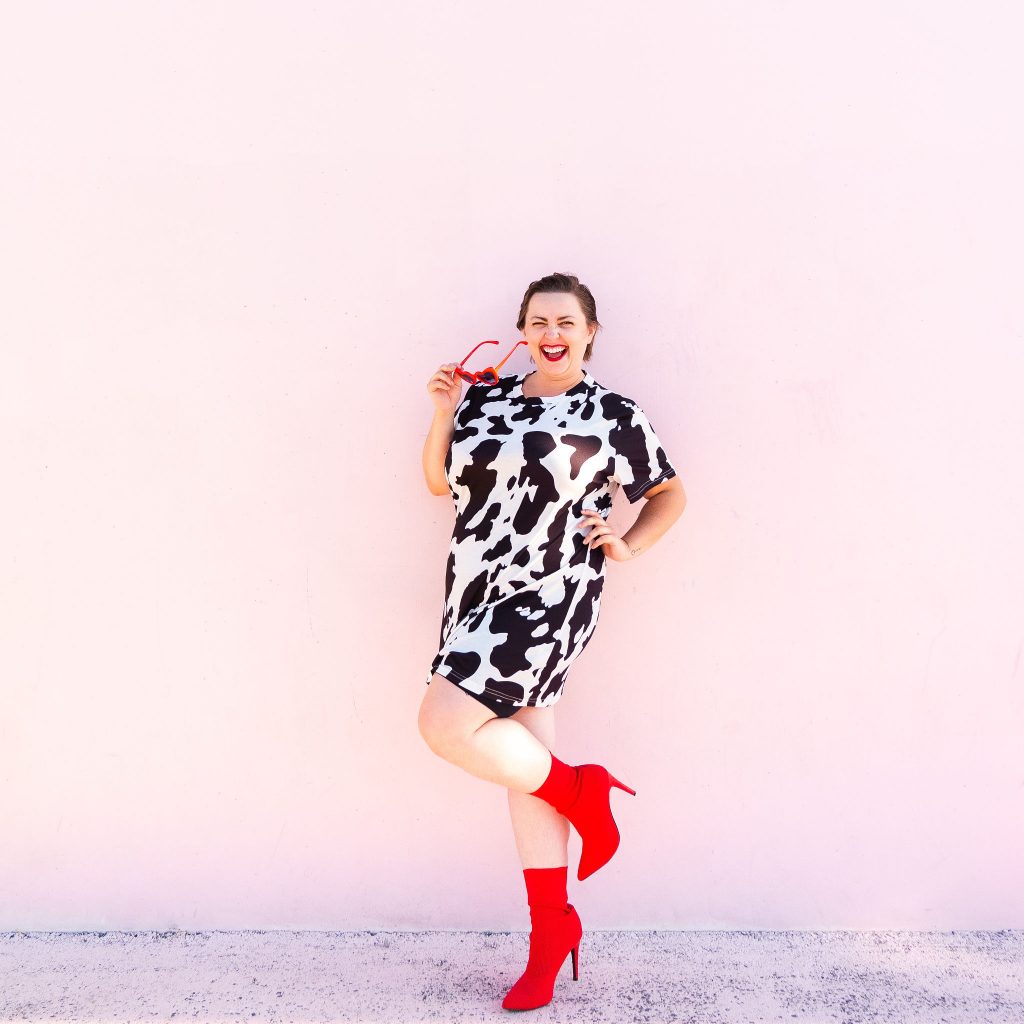 Plus size model in cow print t-shirt dress with red boots in Utah