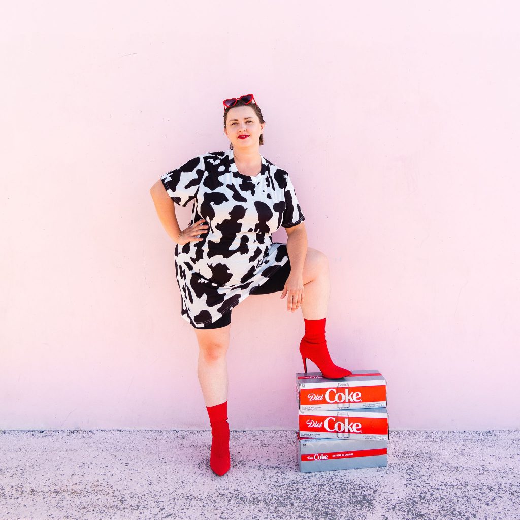 Snack blogger with diet coke and red heart sunglasses in cow print dress with red boots 2