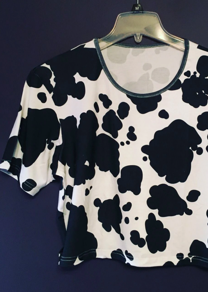 Shopping guide for cow print plus size clothing - image shows a cow print crop top on a hanger