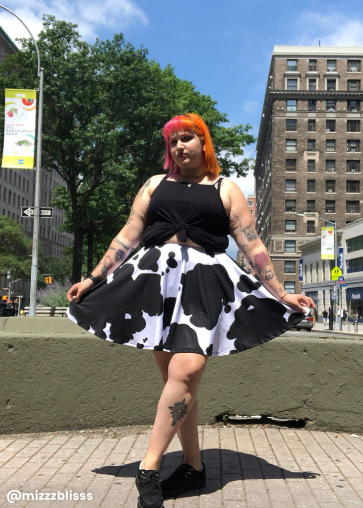 Shopping guide for cow print plus size clothing - model wearing a plus size cow print skirt with black top