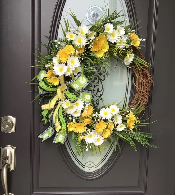 Front Door Wreaths for Summer - fully yellow and white daises arranged against a brown twig wreath base, with about 1/4 of the base showing.  The wreath features a ribbon bow on its side with bright spring green, black and daisy ribbons.
