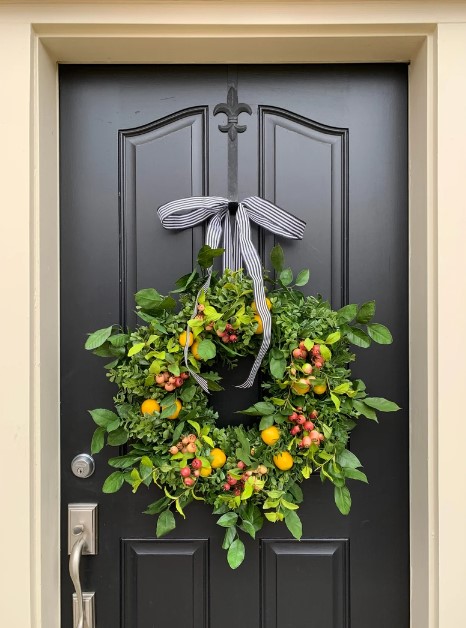 Front Door Wreaths for Summer - lemon wreath with hollly berries on green leafy wreath against a black door.  the wreath has a black and white striped ribbon.