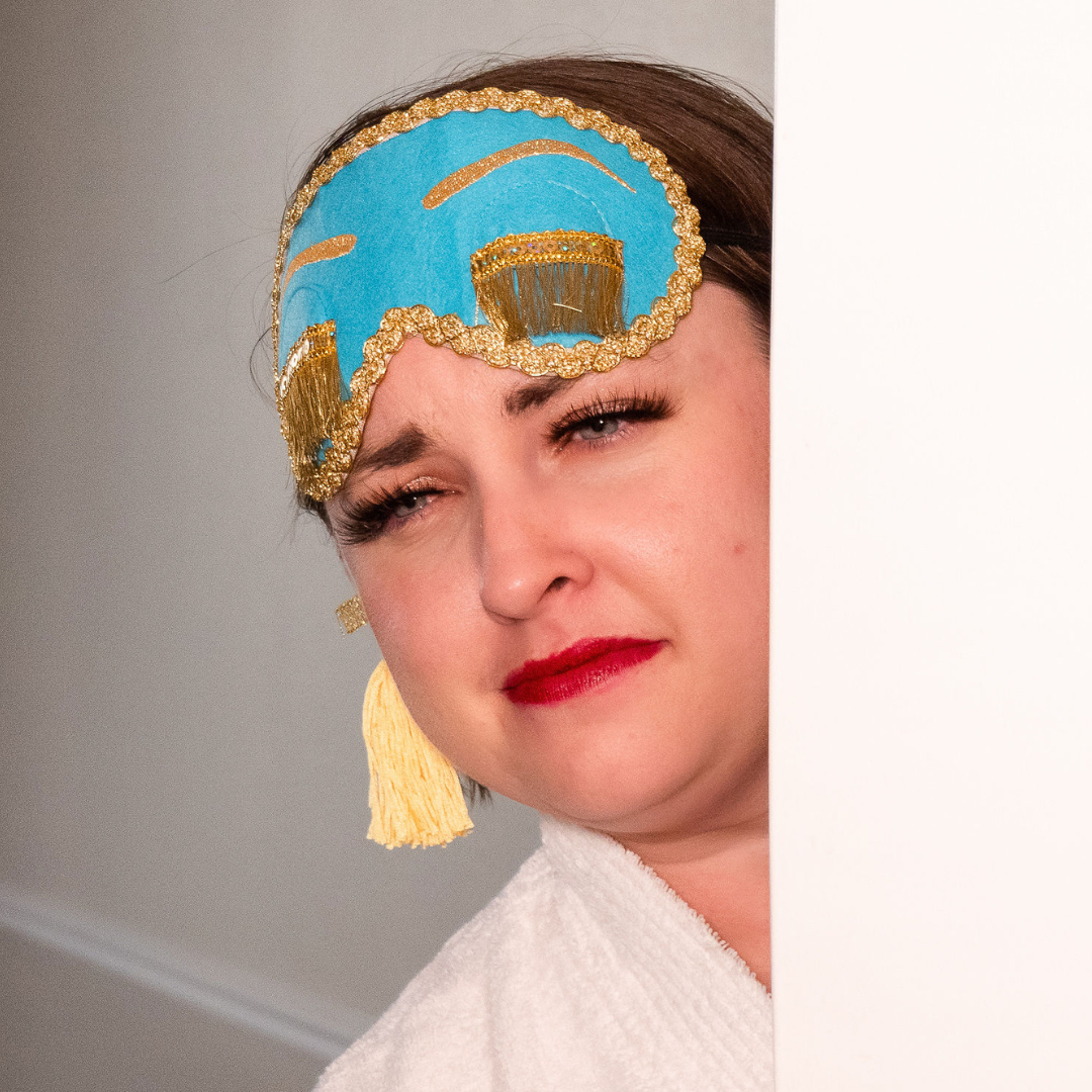 Brianne posing, with just her face shown, showing the eye mask and tassled ear plugs.  She's wearing the iconic bright Tiffany blue sleep mask that was in the movie Breakfast at Tiffany's